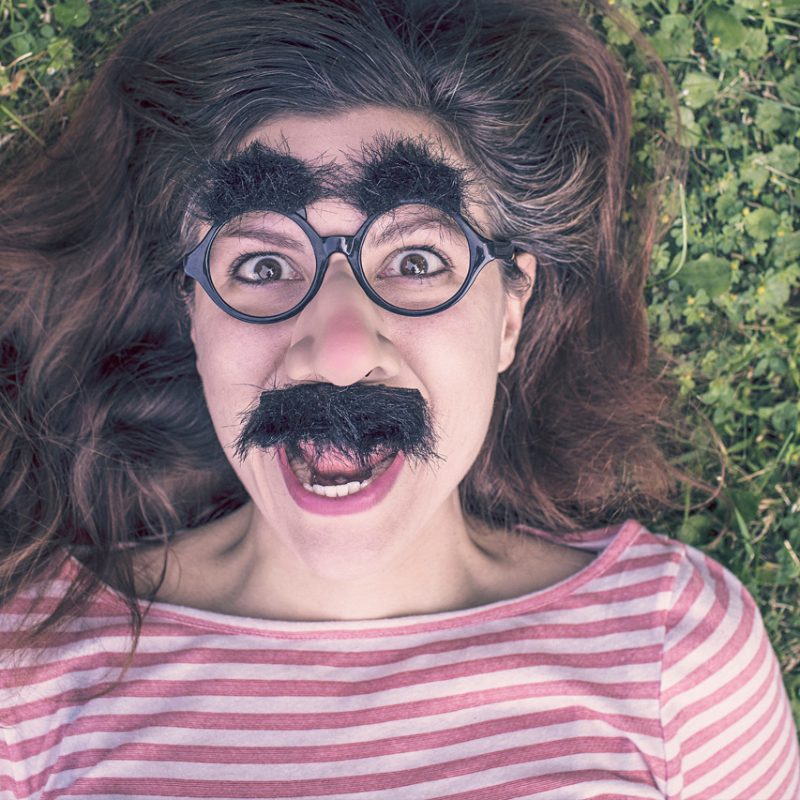 Story IQ girl with bushy eyebrows and moustache lying on grass