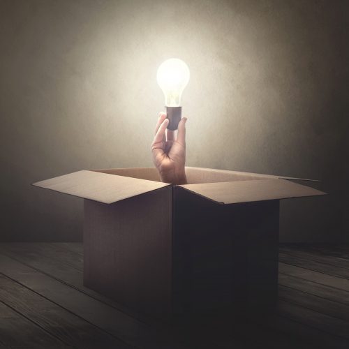 Hand coming out of cardboard box holding lightbulb Story IQ